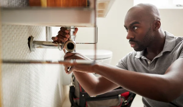a male plumber fixing a pipe connection from Real and Actual in Leander, TX - Plumber near me